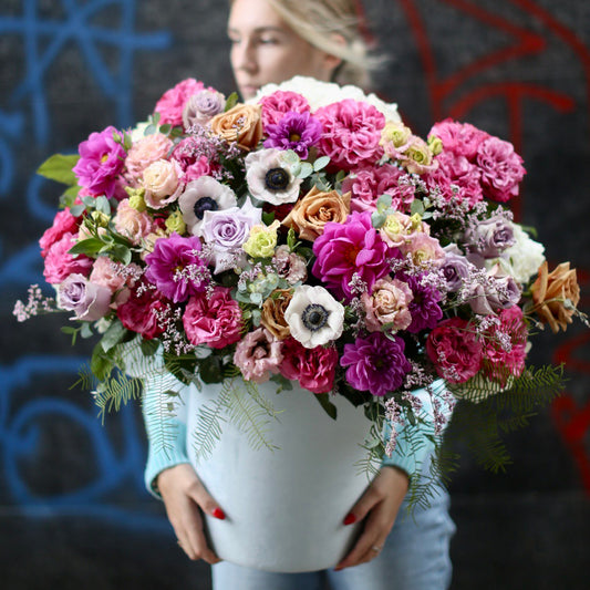 Luxurious anemone-centered bouquet with soft pink accents and lush foliage, styled for premium gifting