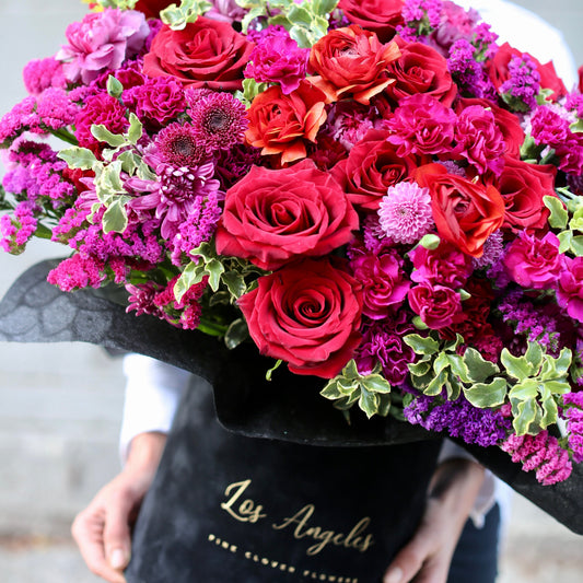 Elegant floral arrangement featuring red roses and colorful seasonal blooms in a stylish keepsake box, beautifully presented for luxury gifting
