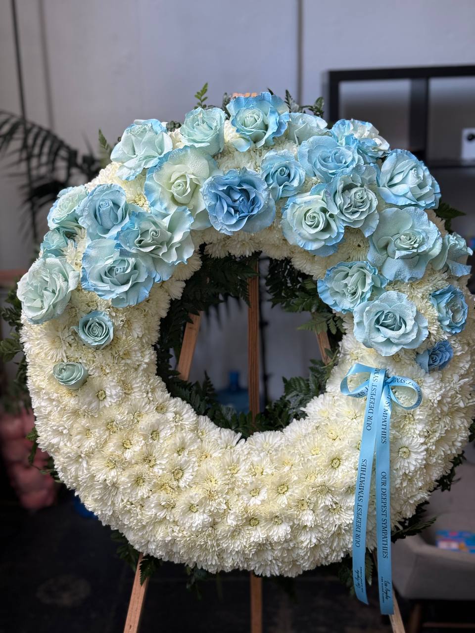 Artisan-crafted blue rose arrangement in a circular design, styled with cascading greenery