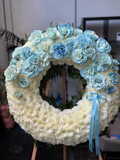 Artisan-crafted blue rose arrangement in a circular design, styled with cascading greenery