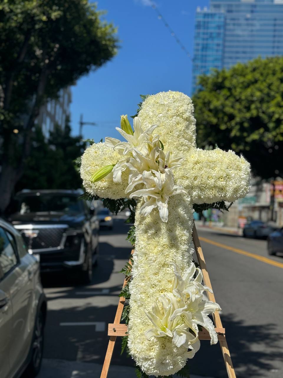 Elegant white lily cross arrangement with lush greenery, symbolizing hope and comfort