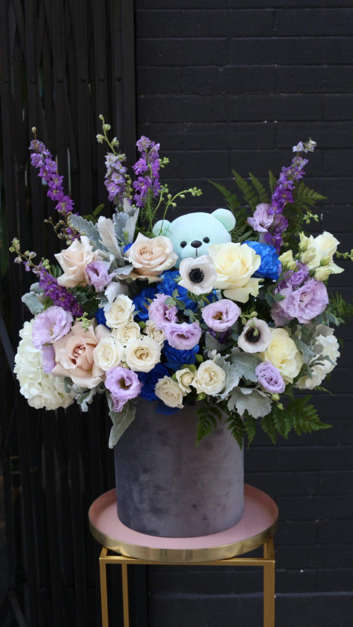 Vibrant Royal Blue Roses paired with soft pink Eustoma and delicate Delphinium blooms in a glass vase.
