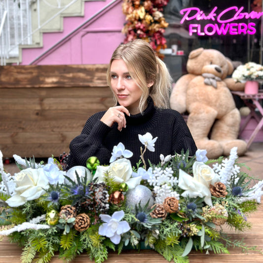 Festive holiday bouquet with white blooms and natural pinecones, arranged in a modern, celebratory style