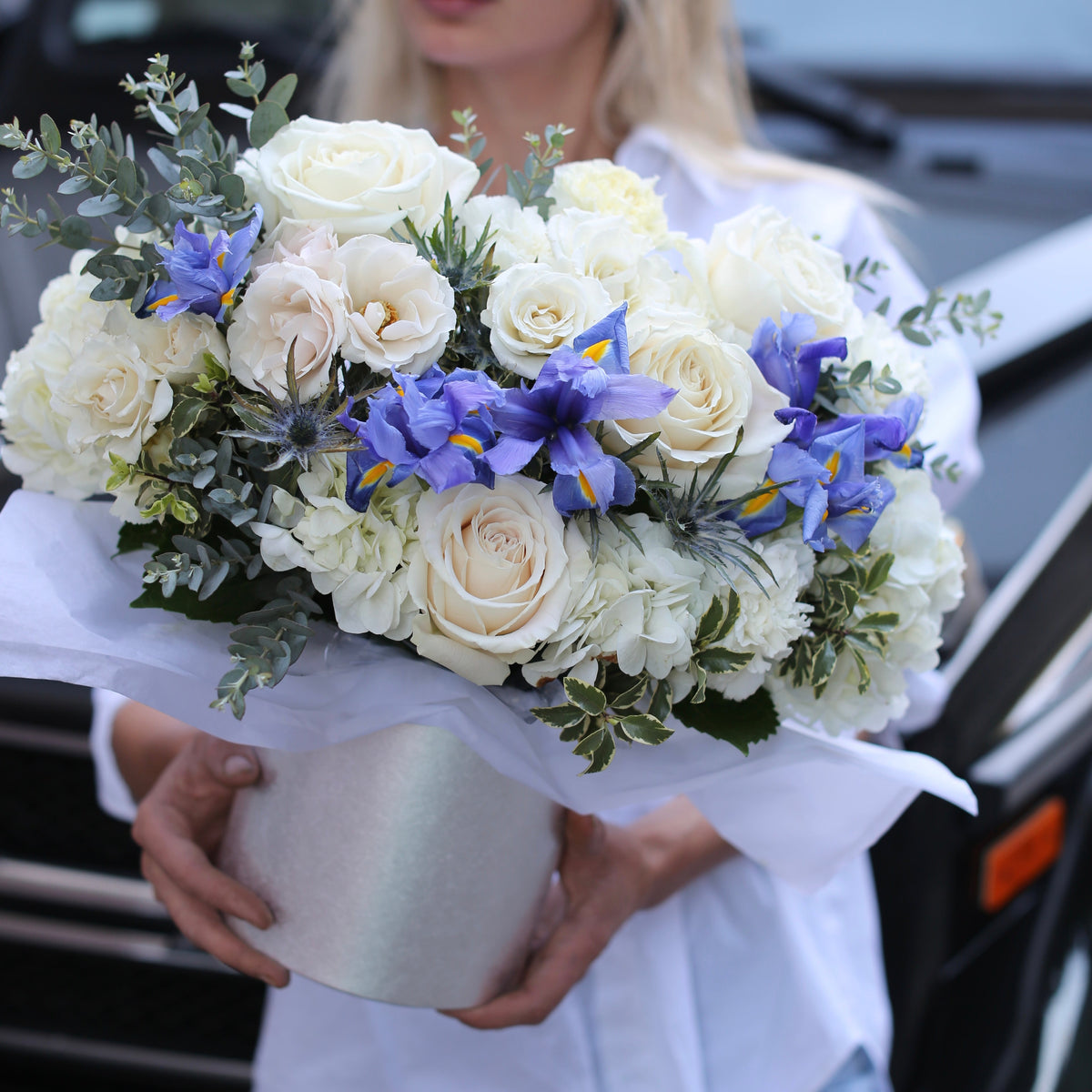 Elegant floral arrangement featuring white roses, irises and mixed flowers in a decorative keepsake box, styled for premium gifting