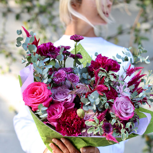 Luxurious Monica bouquet with purple roses and mixed blooms in a clear glass vase, ideal for premium floral gifting