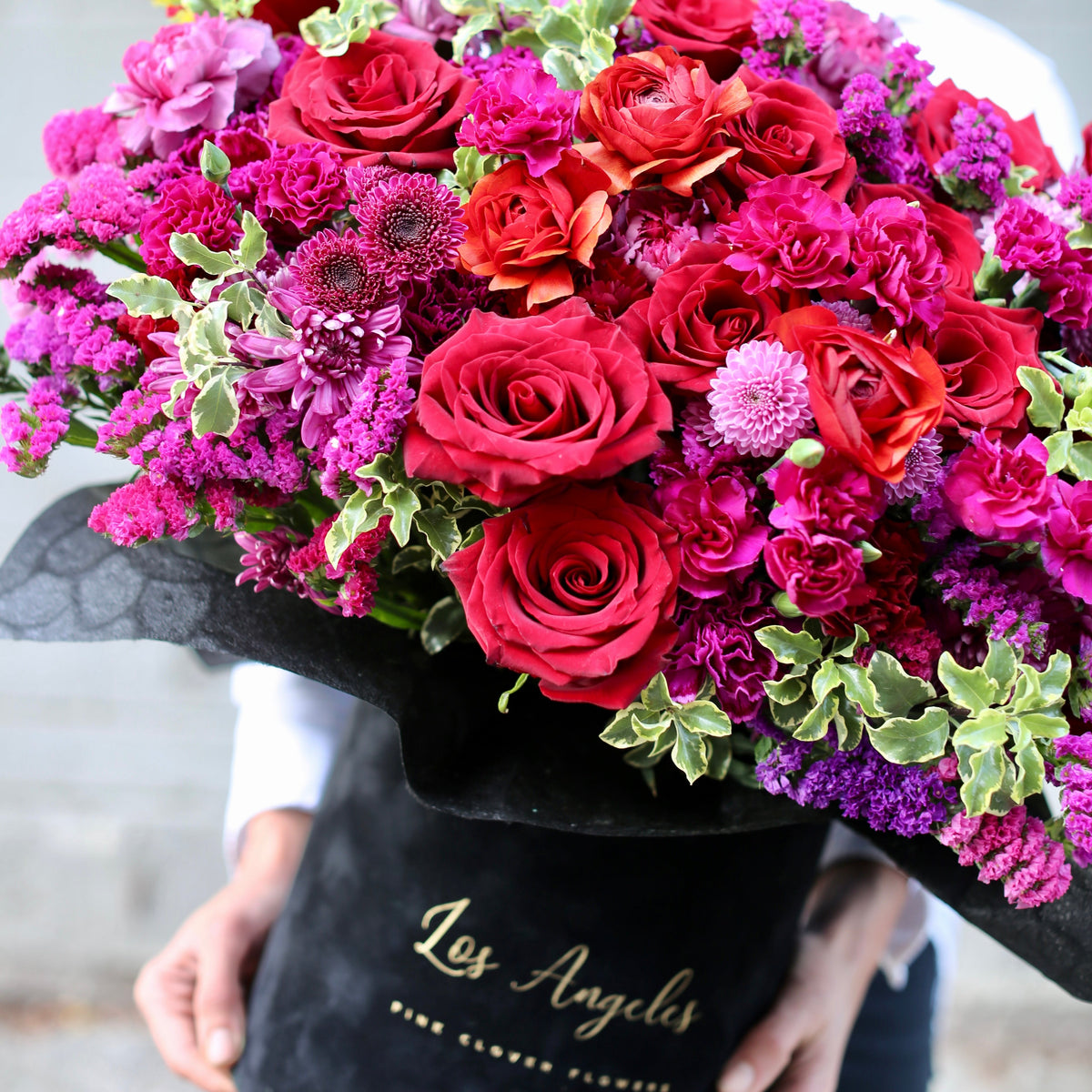 Elegant floral arrangement featuring red roses and colorful seasonal blooms in a stylish keepsake box, beautifully presented for luxury gifting