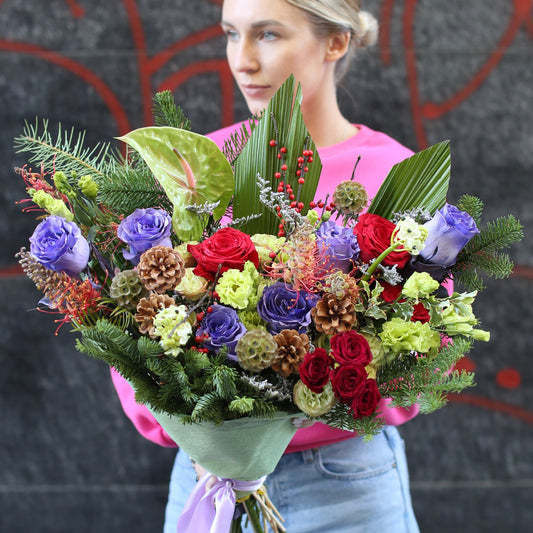 Luxurious Christmas bouquet with red roses, pinecones and festive greenery arranged in a classic holiday style