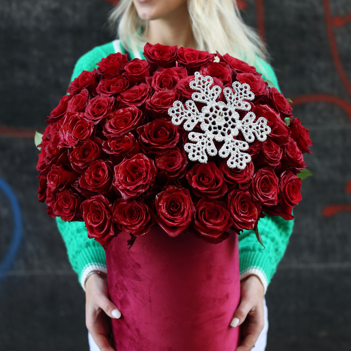 Elegant Christmas flower box with red roses, pinecones, and festive greenery arranged in a celebratory style