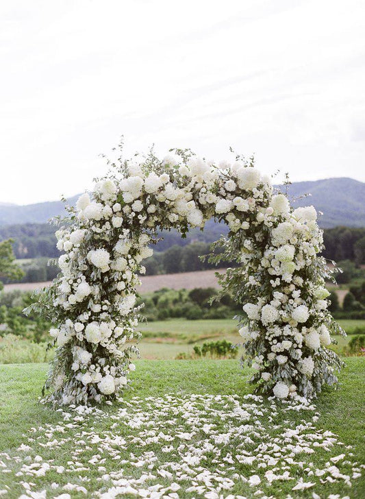 Round wedding arch with blush peonies and ivory roses, styled with cascading greenery for romantic ceremonies
