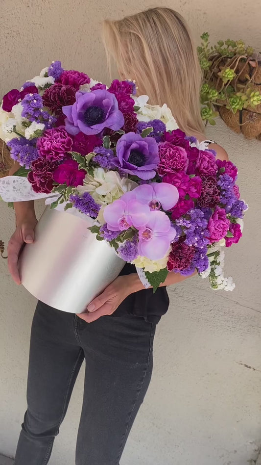 Luxurious floral arrangement with purple blooms and lush greenery, ideal for romantic occasions and upscale celebrations