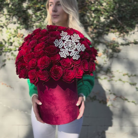 Festive floral gift with vibrant red roses and natural holiday accents, beautifully styled for Christmas
