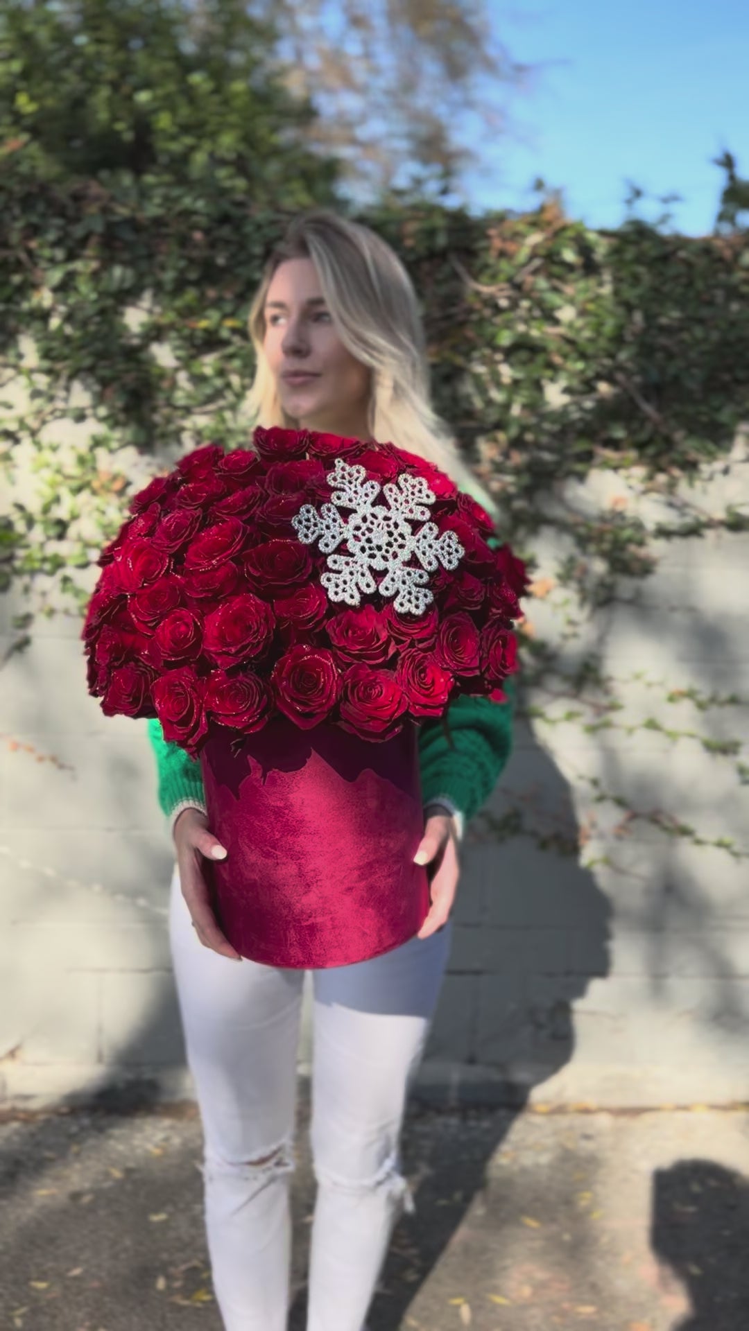 Festive floral gift with vibrant red roses and natural holiday accents, beautifully styled for Christmas