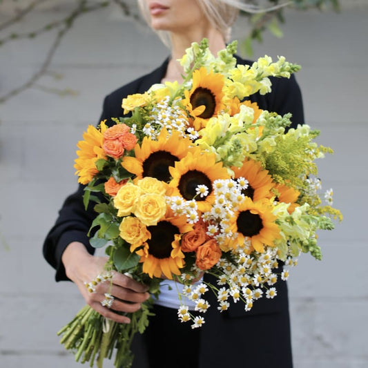 Cheerful bouquet showcasing radiant yellow sunflowers with soft pink accents, arranged in a lively and elegant style